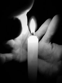 Cropped image of hand holding glass over black background
