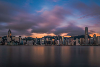 Modern skyscrapers at victoria harbour against cloudy sky