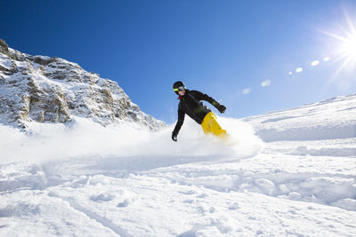 Man skiing on snowcapped mountain against sky