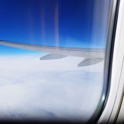 Airplane flying over landscape against blue sky