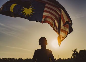 Low angle view of silhouette boy against sky during sunset