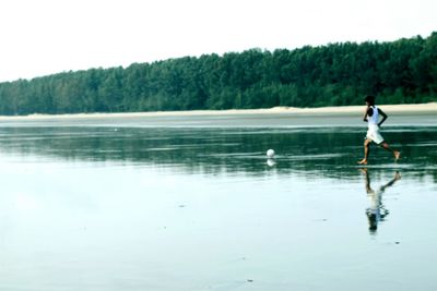 Reflection of man in lake against clear sky