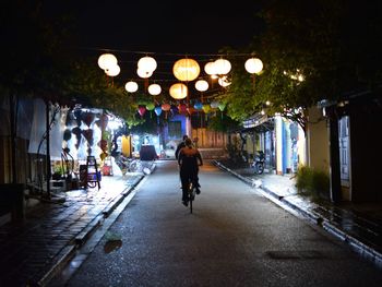 Rear view of man on illuminated street at night