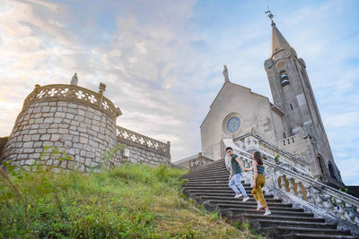 Low angle view of couple moving up on staircase against church
