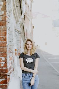 Portrait of beautiful young woman standing against building