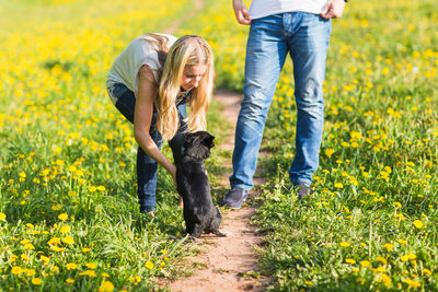 Rear view of woman with dog on yellow flowers