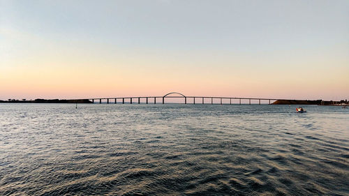 Bridge over sea against clear sky during sunset