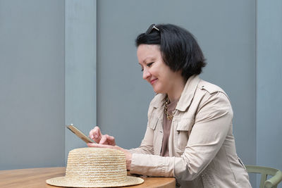 Side view of young woman reading book on table