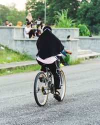 Rear view of man riding bicycle on street