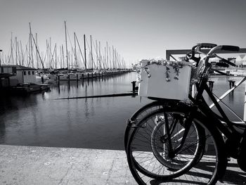 Bicycle by harbor against clear sky