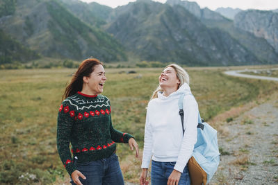 Happy young women travellers on road against beautiful mountain landscape