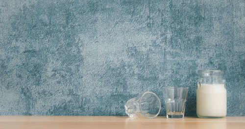 Glass of jar on table against wall