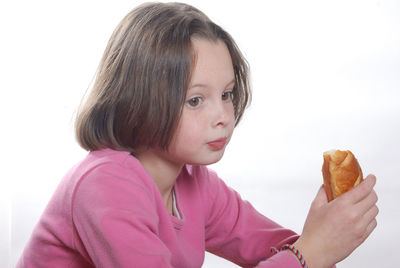 Side view of girl eating food against white background