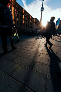 People walking in city against sky during sunset