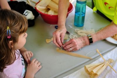 Girl looking at person making decoration on table