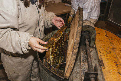 Female beekeeper putting beehive in storage tank at shed