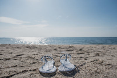 High angle view of shoes on sand at beach against sky