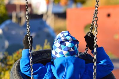 Rear view of boy on swing at playground