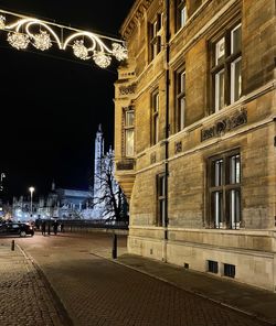 Illuminated street light by building in city at night