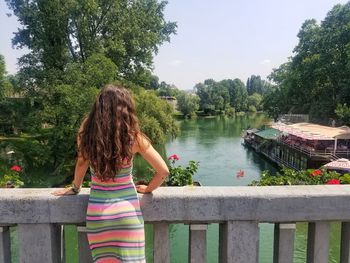 Rear view of woman against lake with trees in background