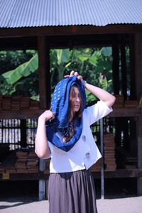 Young woman wearing headscarf standing against built structure