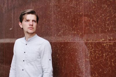 Portrait of handsome man standing against wall