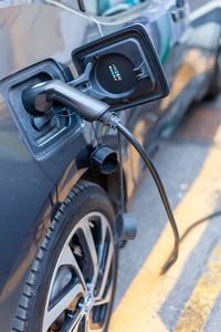 A cable is recharging an electric car at the charging station