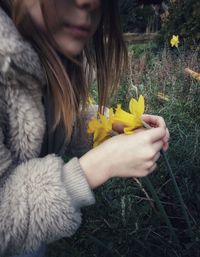 Midsection of woman holding yellow flowering plants