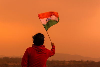 Rear view of man holding indian flag against clear sky