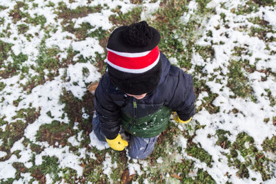 High angle view of child in warm clothing on snow covered field