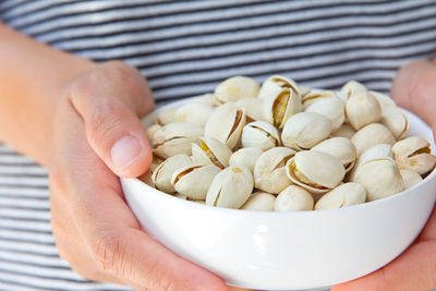 Midsection of man holding pistachios in bowl