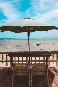 Chairs and table at beach against sky