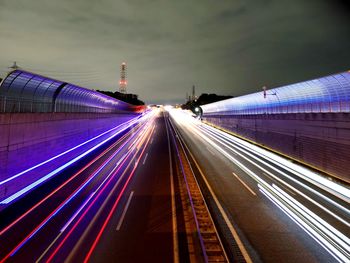 Light trails on road in city against sky at night