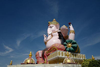 Low angle view of statue against temple building against sky