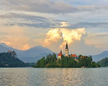 Scenic view of lake and buildings against sky during sunset