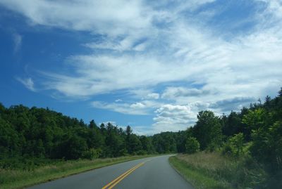 Empty road amidst trees against sky