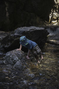 Full length of boy walking on rock in river 