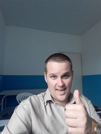 Portrait of happy man gesturing thumbs up in clinic