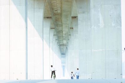 Rear view of people walking under bridge