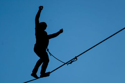 Low angle view of silhouette man against clear blue sky