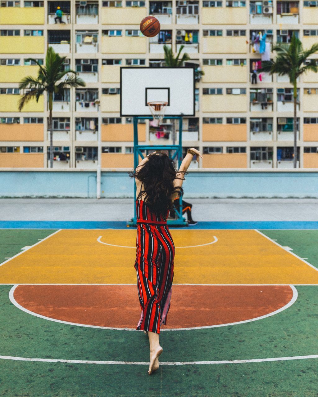 REAR VIEW OF WOMAN PLAYING WITH UMBRELLA IN THE BACKGROUND