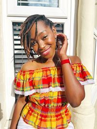 Portrait of young woman standing against wall