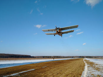 Airplane flying over water against blue sky