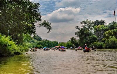 People on boat in river against sky