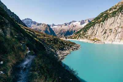 Scenic view of lake and mountains against clear blue sky