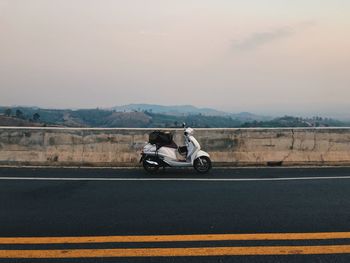 Man riding motorcycle on road against sky