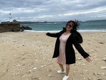 Full length of young woman standing on beach