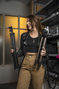 Happy woman holding tripods in studio