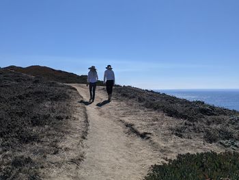 Therapeutic nature. two women walking dirt path along ocean cliffs.