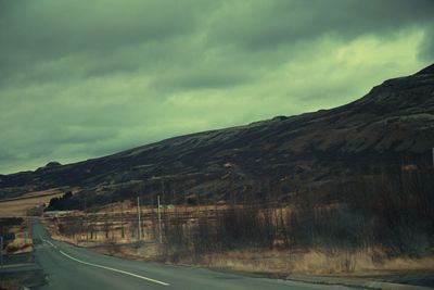 Empty road against cloudy sky